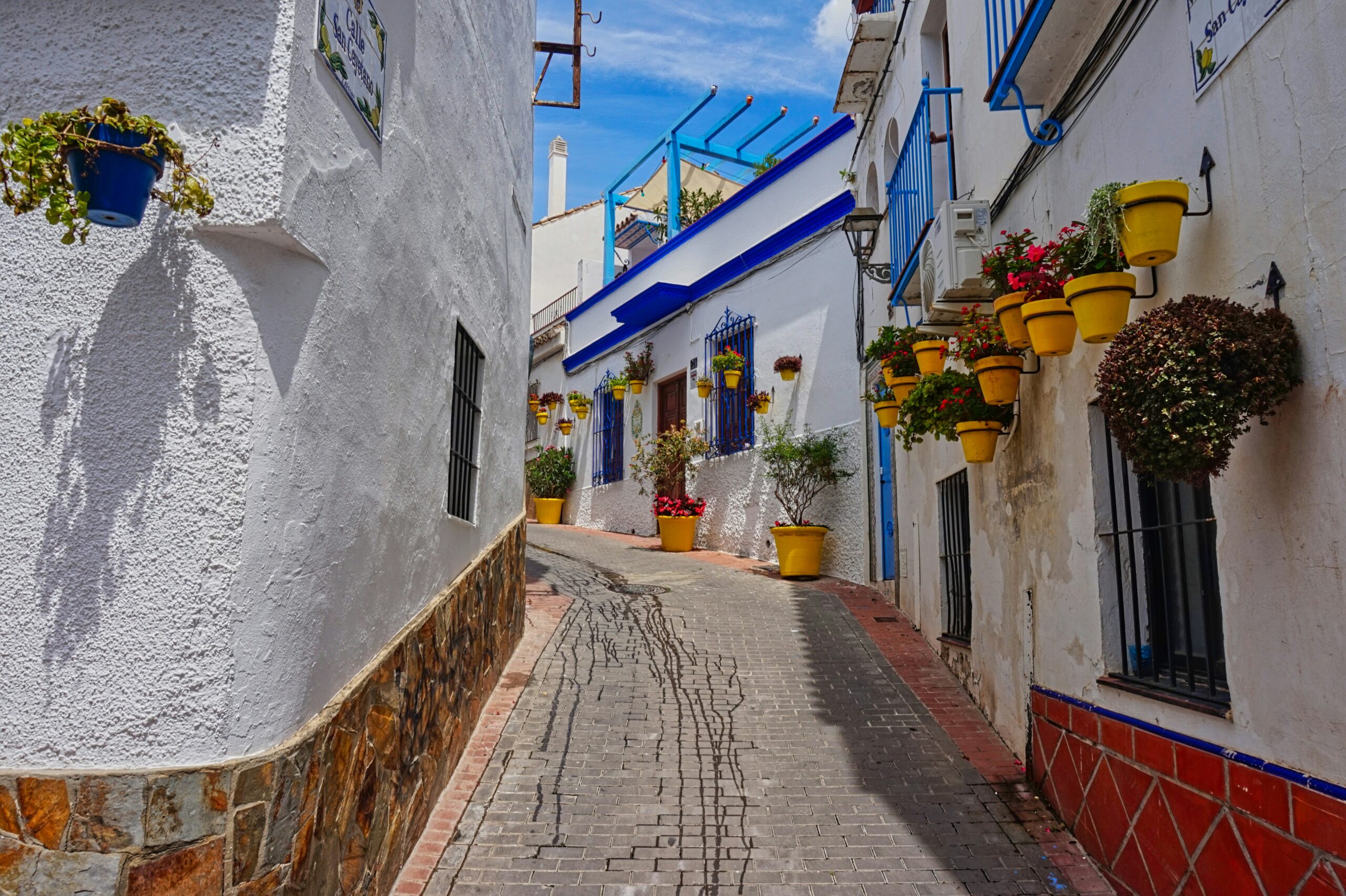 Charmante smalle straat met witte muren en kleurrijke bloemenpotten in Estepona.