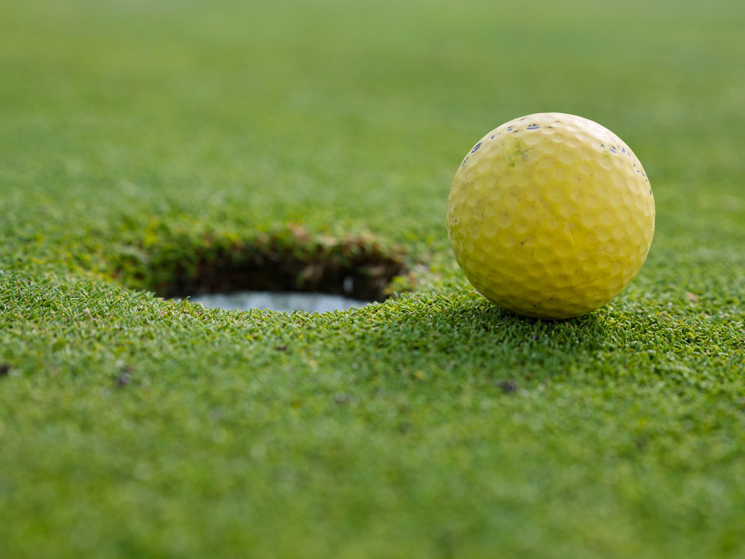 Golfbal naast hole op groene golfbaan in Estepona.